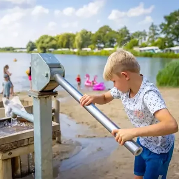 Kind spelend bij visvijver met waterpomp